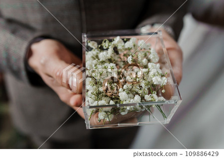 Box with gold wedding rings in the hands of the groom 109886429
