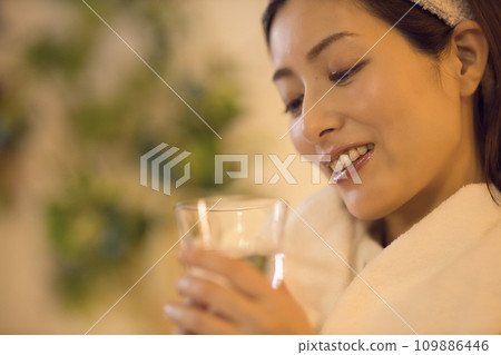 Night routine of a woman drinking water after taking a bath Night routine of a woman drinking water after taking a bath 109886446