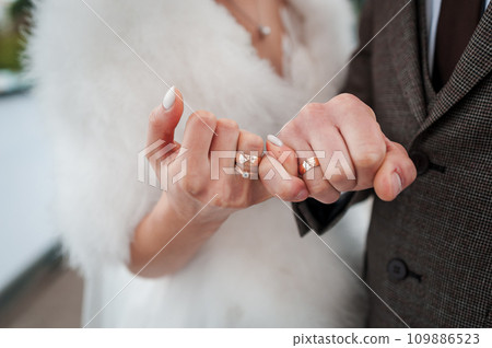 Golden wedding rings on the hands of the bride and groom Golden wedding rings on the hands of the bride and groom 109886523