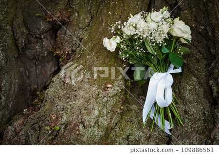 Beautiful wedding bouquet on a wood background. Bride's bouquet with white roses on a brown background Beautiful wedding bouquet on a wood background. Bride's bouquet with white roses on a brown background 109886561