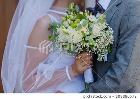 A beautiful wedding bouquet in the hands of the bride. Bouquet with white flowers in the hands of the bride 109886572