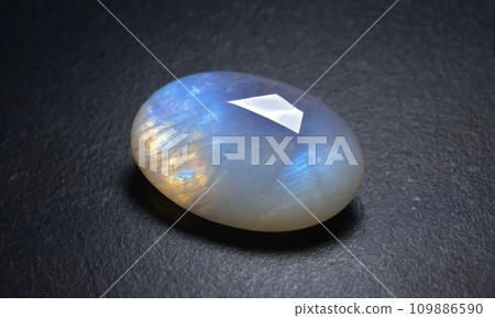 Natural precious moonstone on a gray background. Natural stone adularia Natural precious moonstone on a gray background. Natural stone adularia 109886590