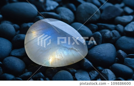 Natural precious moonstone on a gray background. Natural stone adularia Natural precious moonstone on a gray background. Natural stone adularia 109886600