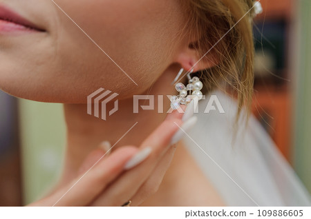 Earrings for a woman's ear. Woman fastening an earring 109886605