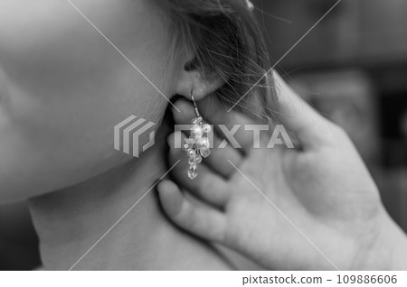 Earrings for a woman's ear. Woman fastening an earring 109886606