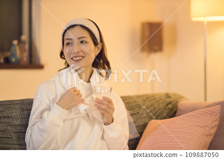 Night routine of a woman drinking water after taking a bath Night routine of a woman drinking water after taking a bath 109887050