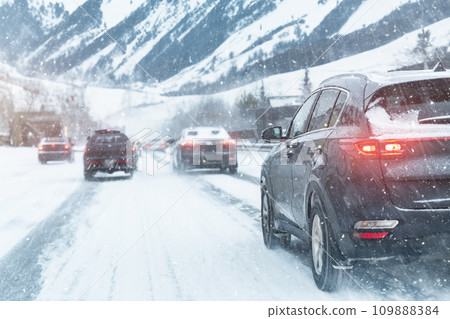 Scenic view snow covered city highway slippery mountain alpine road drive cars moving fast speed motion. Snowfall danger blizzard bad winter weather conditions. Cold snowy day snowstorm background 109888384
