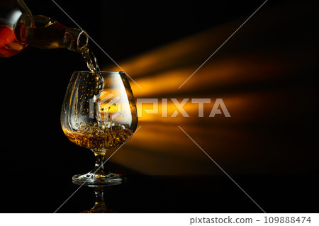 Pouring brandy from a bottle into a snifter. 109888474