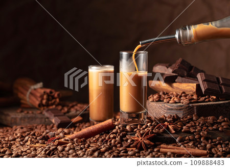 Irish cream and coffee liquor is poured from a bottle into a glass. 109888483