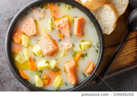 Creamy fish soup with salmon, potatoes, onions, carrots, dill and celery close-up on a plate. Horizontal top view Creamy fish soup with salmon, potatoes, onions, carrots, dill and celery close-up on a plate. Horizontal top view 109889208