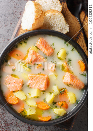 Finnish wild salmon soup with cream and root vegetables close-up on a plate. Vertical top view Finnish wild salmon soup with cream and root vegetables close-up on a plate. Vertical top view 109889211