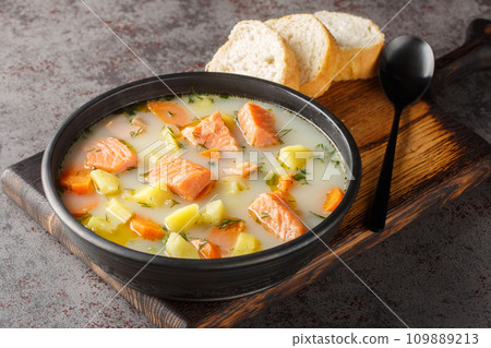 Creamy soup with red fish, potatoes, onions, carrots, celery and green dill in a bowl. Horizontal 109889213