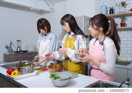Three women making salad in the kitchen 109890073