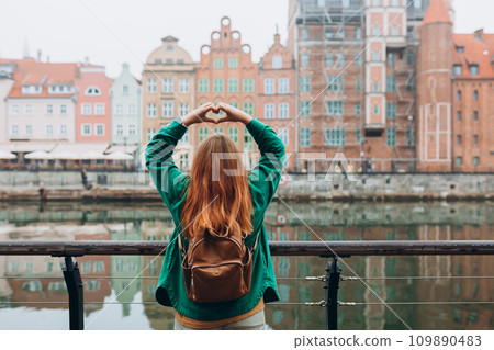 Adventure women making by hands in shape of love heart. Attractive young female tourist is exploring new city. Traveling Europe in autumn, rainy day, rear view Adventure women making by hands in shape of love heart. Attractive young female tourist is exploring new city. Traveling Europe in autumn, rainy day, rear view 109890483