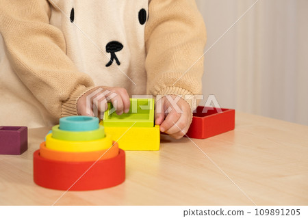 Little boy playing with wooden multicolored Montessori toys. Hands close-up Little boy playing with wooden multicolored Montessori toys. Hands close-up 109891205