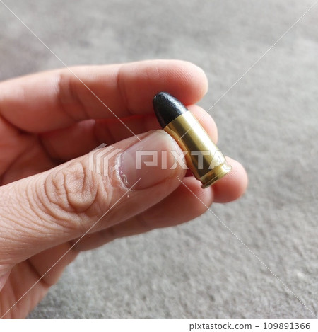 Close up of 9mm bullet in hand, sport shooting range. Small bullet in a hand. 109891366