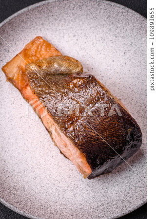 Fresh cooked delicious salmon steak with spices and herbs baked on a grill Fresh cooked delicious salmon steak with spices and herbs baked on a grill 109891655