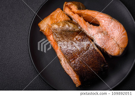 Fresh cooked delicious salmon steak with spices and herbs baked on a grill Fresh cooked delicious salmon steak with spices and herbs baked on a grill 109892051