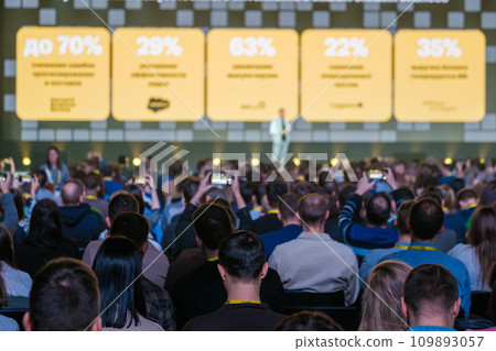 Moscow, November 30, 2023: Diverse business crowd attending global workshop in huge auditorium with number data on projection screen Moscow, November 30, 2023: Diverse business crowd attending global workshop in huge auditorium with number data on projection screen 109893057