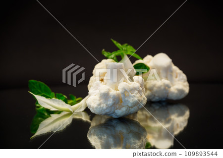 slices of raw small raw cauliflower on black background 109893544
