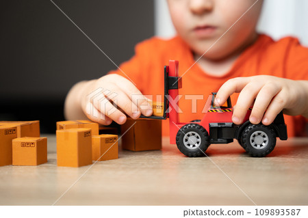 A child plays in loading boxes with a toy forklift. Warehouses, manufacturing facilities, and distribution centers. Inventory accuracy. Efficient logistics and distribution systems. A child plays in loading boxes with a toy forklift. Warehouses, manufacturing facilities, and distribution centers. Inventory accuracy. Efficient logistics and distribution systems. 109893587