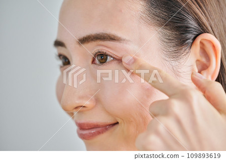 A woman in her 30s putting her finger on her left eye A woman in her 30s putting her finger on her left eye 109893619