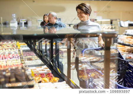 Woman chooses cakes at showcase of confectionery department 109893897