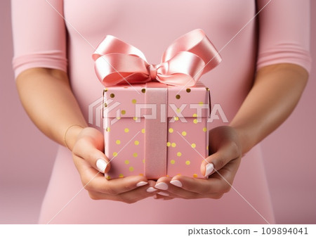 female hands holding a pink gift box 109894041