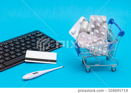 Ordering Medicines. Pills and Capsules in a Shopping Cart on Blue Background Ordering Medicines. Pills and Capsules in a Shopping Cart on Blue Background 109895719