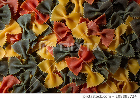 Dry Uncooked Colored Farfalle Pasta and Raw Macaroni on a Textured Background 109895724