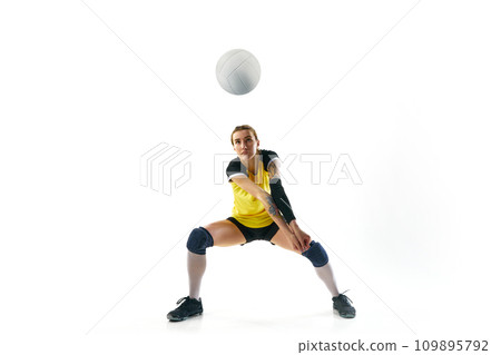Concentrated young woman in uniform training, playing volleyball, hitting ball isolated over white background. Sport, active and healthy lifestyle Concentrated young woman in uniform training, playing volleyball, hitting ball isolated over white background. Sport, active and healthy lifestyle 109895792