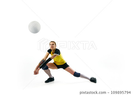 Concentrated young woman in uniform training, playing volleyball, hitting ball isolated over white background. Sport, active and healthy lifestyle Concentrated young woman in uniform training, playing volleyball, hitting ball isolated over white background. Sport, active and healthy lifestyle 109895794