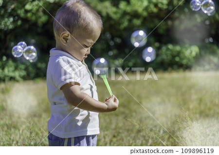 一個男孩在公園裡盯著肥皂泡 一個男孩在公園裡盯著肥皂泡 109896119