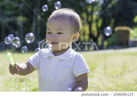 Boy playing with soap bubbles in the park Boy playing with soap bubbles in the park 109896125