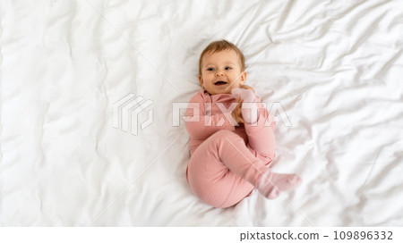 Adorable caucasian baby girl laying on bed, playing with feet and smiling, top view, panorama with copy space Adorable caucasian baby girl laying on bed, playing with feet and smiling, top view, panorama with copy space 109896332
