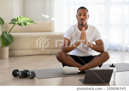 Peaceful african american man meditating at home, using laptop Peaceful african american man meditating at home, using laptop 109896345