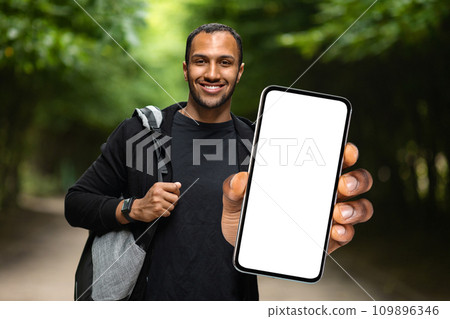Sports App. Athletic young black man standing outdoors and showing blank smartphone Sports App. Athletic young black man standing outdoors and showing blank smartphone 109896346