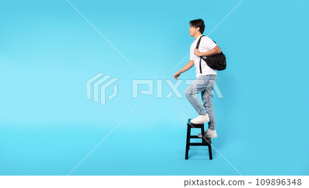 Korean Guy Walking Up Stairs On Ladder Over Blue Background Korean Guy Walking Up Stairs On Ladder Over Blue Background 109896348