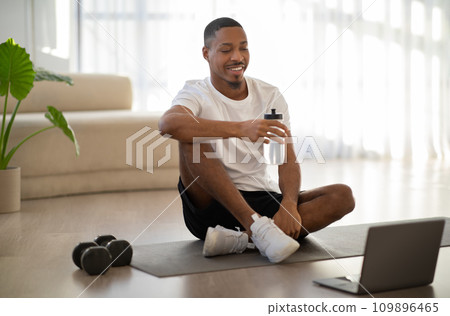 Cheerful black guy exercising at home, drinking water 109896465