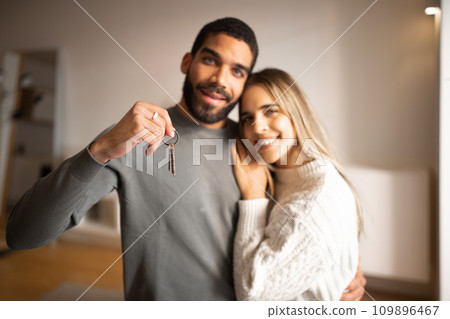Cheerful young arab man hugging european wife, show keys, enjoy new home, celebration rental property 109896467
