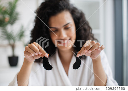Focus on hands of charming multinational serene female with black eye gels Focus on hands of charming multinational serene female with black eye gels 109896560