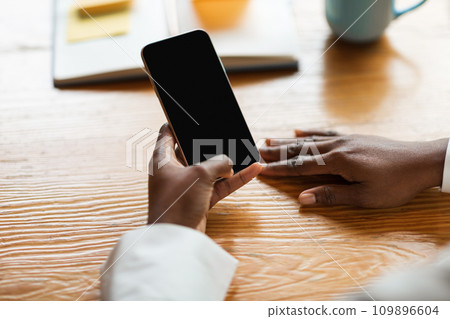 Cropped of black woman holding cell phone with empty screen Cropped of black woman holding cell phone with empty screen 109896604