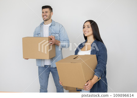 Moving Concept. Happy Young Couple With Cardboard Boxes Standing In Empty Room Moving Concept. Happy Young Couple With Cardboard Boxes Standing In Empty Room 109896614