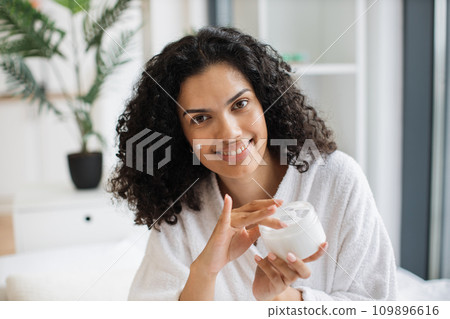 Close up portrait of young multinational woman with cream on cheek Close up portrait of young multinational woman with cream on cheek 109896616