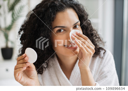 Multiracial woman removing cosmetics from nose area 109896634