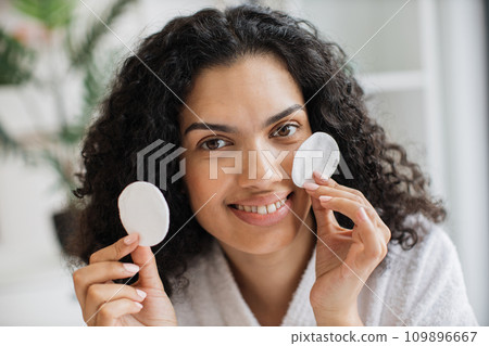 Portrait of young multiracial woman holding cotton cosmetic sponges Portrait of young multiracial woman holding cotton cosmetic sponges 109896667