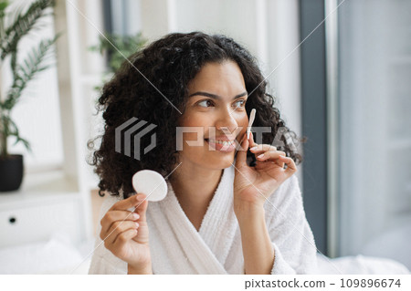 Young multiracial woman holding cotton cosmetic sponges Young multiracial woman holding cotton cosmetic sponges 109896674