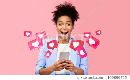 Glad surprised young african american woman with open mouth has romantic chat with hearts on phone 109896735