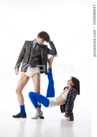 Attractive man in underwear and jacket using leg of young girl in blue tights like stand, armrest against white studio background. 109896847