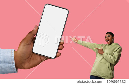 Excited African American Lady Pointing At Huge Smartphone In Female Hand 109896882
